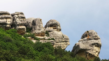 Fototapeta na wymiar Sandy cliffs stones-idols against sky