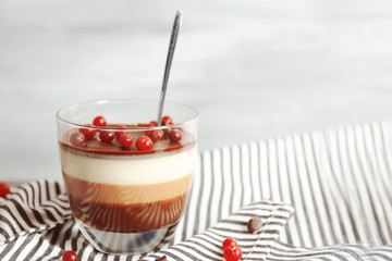 Delicious dessert with rowan in glass on table