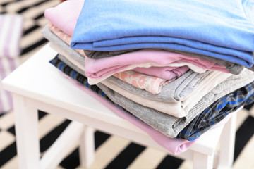 Stack of folded clothes on wooden stool closeup