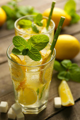 Two lemonades with lemons, mint and sugar cubes on wooden table background, closeup