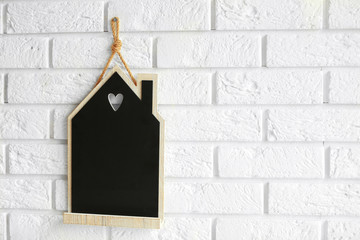 House shaped chalkboard hanging on brick wall, closeup