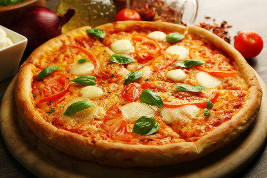 Margherita pizza with tomatoes and spices on wooden background