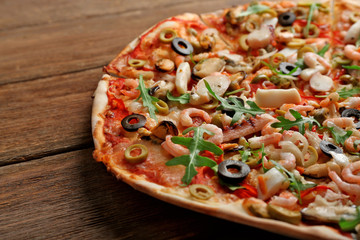Pizza with seafood, red pepper and olives on wooden table
