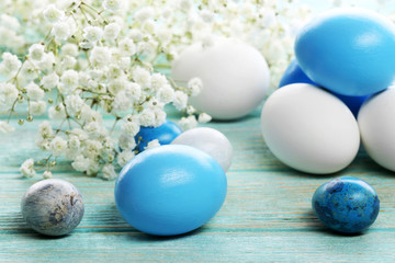 Fototapeta na wymiar Blue and white Easter eggs with flowers on wooden table closeup