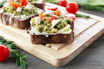 Avocado sandwiches with tomatoes and mozzarella on cutting board