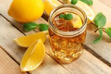 Jar of iced tea with lemon on wooden background