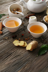 Two cups of brewed tea with ginger and spices on wooden table