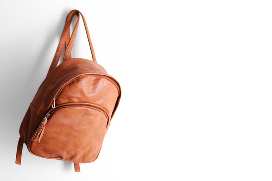 Brown leather backpack hanging on the wall.