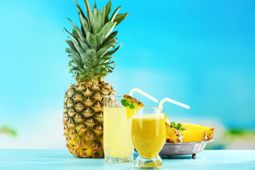 Pineapple juice and smoothie in cocktail glasses on blue blurred background