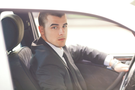 Portrait of a young businessman looking at camera while driving a car