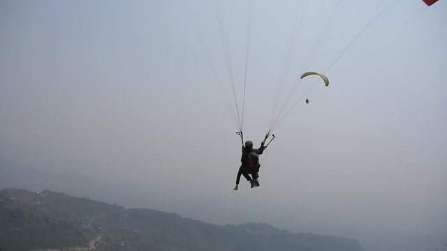 Pilot of the tandem paraglider takes off from the mountainside