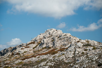Beautiful landscape with rocky mountains and clouds on the western part of Mallorca island, Spain.  Tramuntana mountains with green bushes. Tourist trekking destination in Spain.