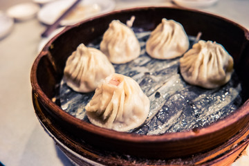 Traditional chinese food, steamed dumpling served on table in a wooden dish and with wooden chopsticks.