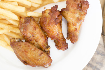 Fast food, crispy chicken wings and french fries on wood backgro