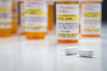 Medicine Bottles and Pills on Reflective Surface With Grey Backg