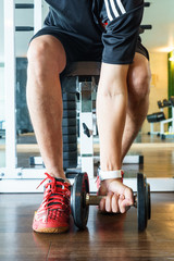 Man exercises with dumbbells in fitness gym