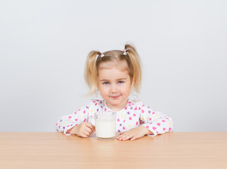 Happy little girl with a glass of milk.