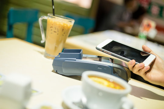 Woman using mobile phone to pay the biil with NFC technology