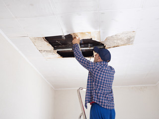 Man repairing collapsed ceiling. - 107030828