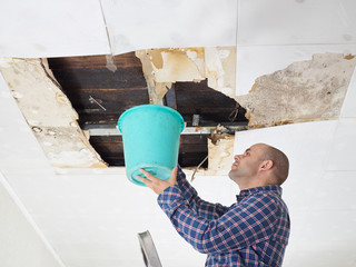  Man Collecting Water In Bucket From Ceiling - 107030869