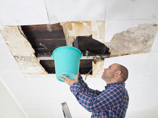  Man Collecting Water In Bucket From Ceiling