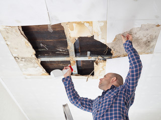 man cleaning mold on ceiling.