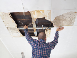 Man repairing collapsed ceiling. - 107030896