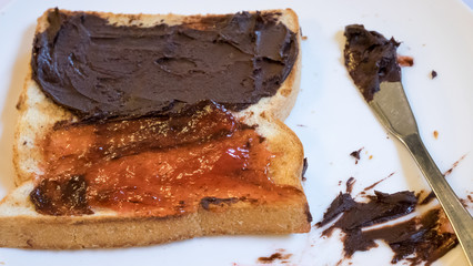 The close up of tasty bread toast and strawberry jam with chocolate spread on white plate.