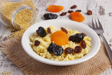 Cooked millet groats on white plate, healthy food and nutrition