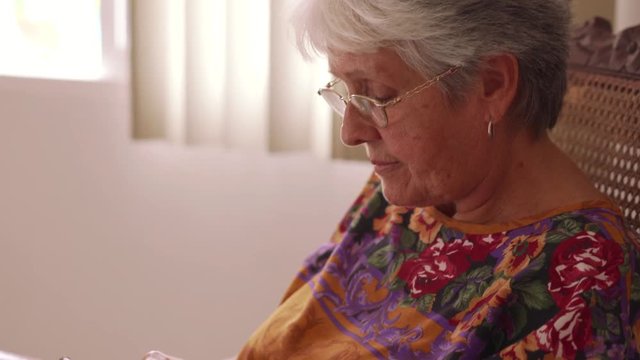 Old people in geriatric hospice: elderly lady having eyesight problems viewing the display of mobile phone. The woman tries to write a text message on tiny keyboard but cannot see the buttons
