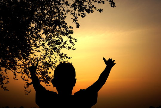 silhouette of a boy watching at sunset, happy enjoying moment, success concept