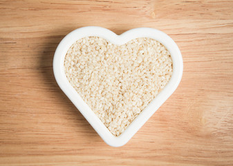 pile of sesame in a heart shape block on a wood background