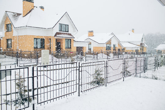 Row of the snowbound houses, homes with the sidewalk on empty strit