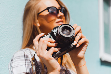Close up lifestyle details,young hike hipster woman holding retro sunglasses,golden jewelry,warm colors.holding vintage retro camera on her hands,stylish classic accessorizes