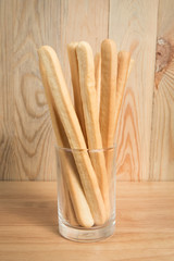 cup of  bread stick in front of a blurry wooden background.Selec