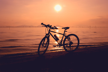 Fototapeta na wymiar Silhouette of bicycle on the beach against colorful sunset