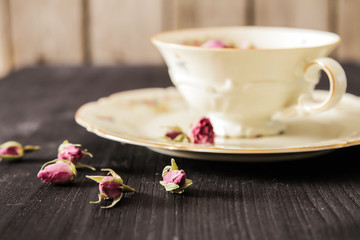 Vintage cup of tea with rosebuds, on black background