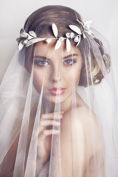 Beautiful bride with fashion wedding hairstyle - on white background.Closeup portrait of young gorgeous bride. Wedding. Studio shot.Beautiful bride portrait with veil over her face