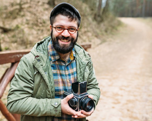 Young man bearded with film photocamera in the forest