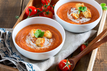 Tomato soup with cream and croutons on a wooden background