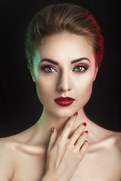 Beautiful elegant young model with red lips and color evening make-up.Woman Face on dark background.Picture taken in the studio.High fashion look.glamor closeup portrait of sexy stylish brunette