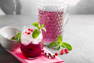 Pink ice cold drinks  with pomegranate and mint on a concrete background