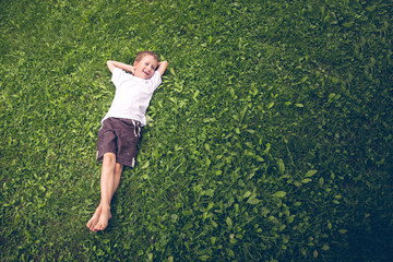 Young boy lying in the grass and laughing - Powered by Adobe