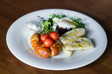 Breakfast with fried sausages, baked cherry tomatoes, poached eg