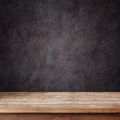 Empty wooden table against a dark wall
