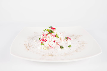 Cottage cheese with radish and chives on a white plate