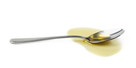 Steel spoon in a puddle of olive oil