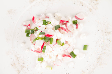 Cottage cheese with radish and chives on a white plate