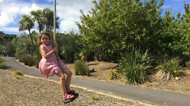 Slow motion child girl (age 05 - 06) rids on Flying Fox play equipment in a children's playground.Child childhood concept