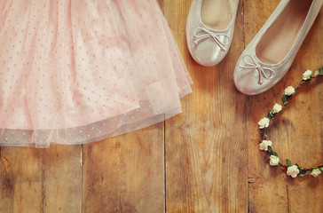 vintage chiffon girl's dress next to ballet shoes on wooden background. vintage filtered image
